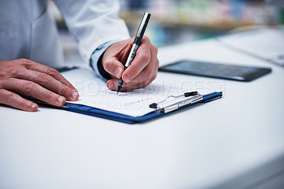 Buy stock photo Closeup shot of an unrecognizable pharmacist writing on a clipboard in a pharmacy