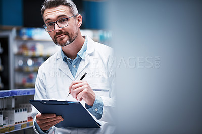 Buy stock photo Portrait of a mature pharmacist writing on a clipboard in a pharmacy