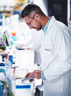 Buy stock photo Shot of a mature pharmacist sorting medication in a pharmacy
