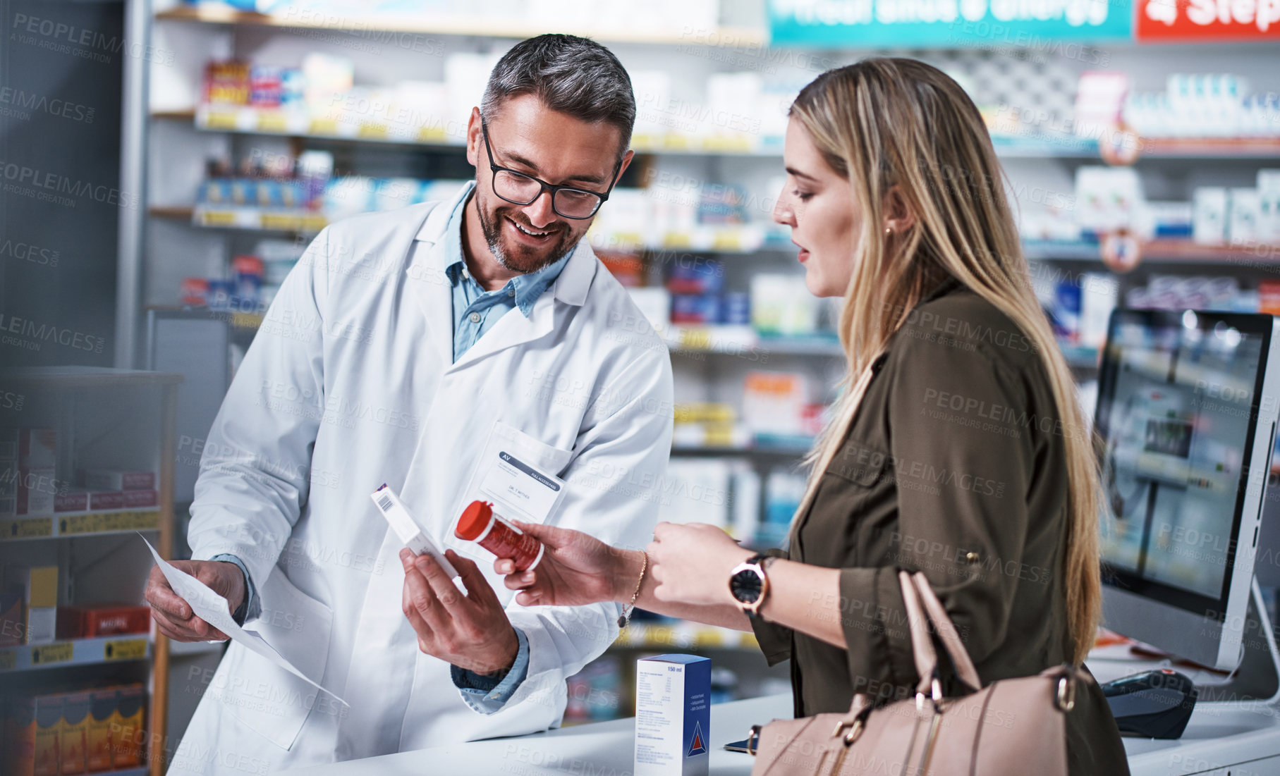 Buy stock photo Shot of a mature pharmacist assisting a young woman in a chemist