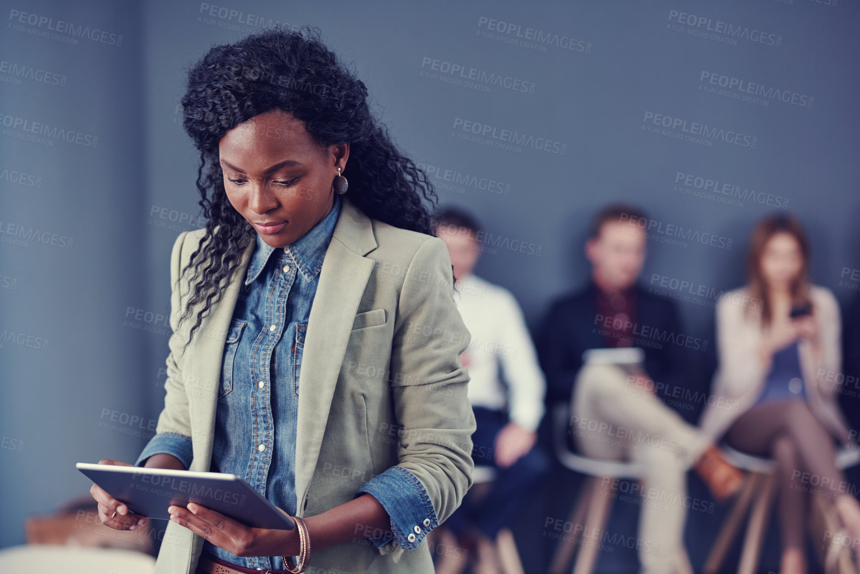 Buy stock photo Cropped shot of an attractive young businesswoman using a tablet with her colleagues in the background