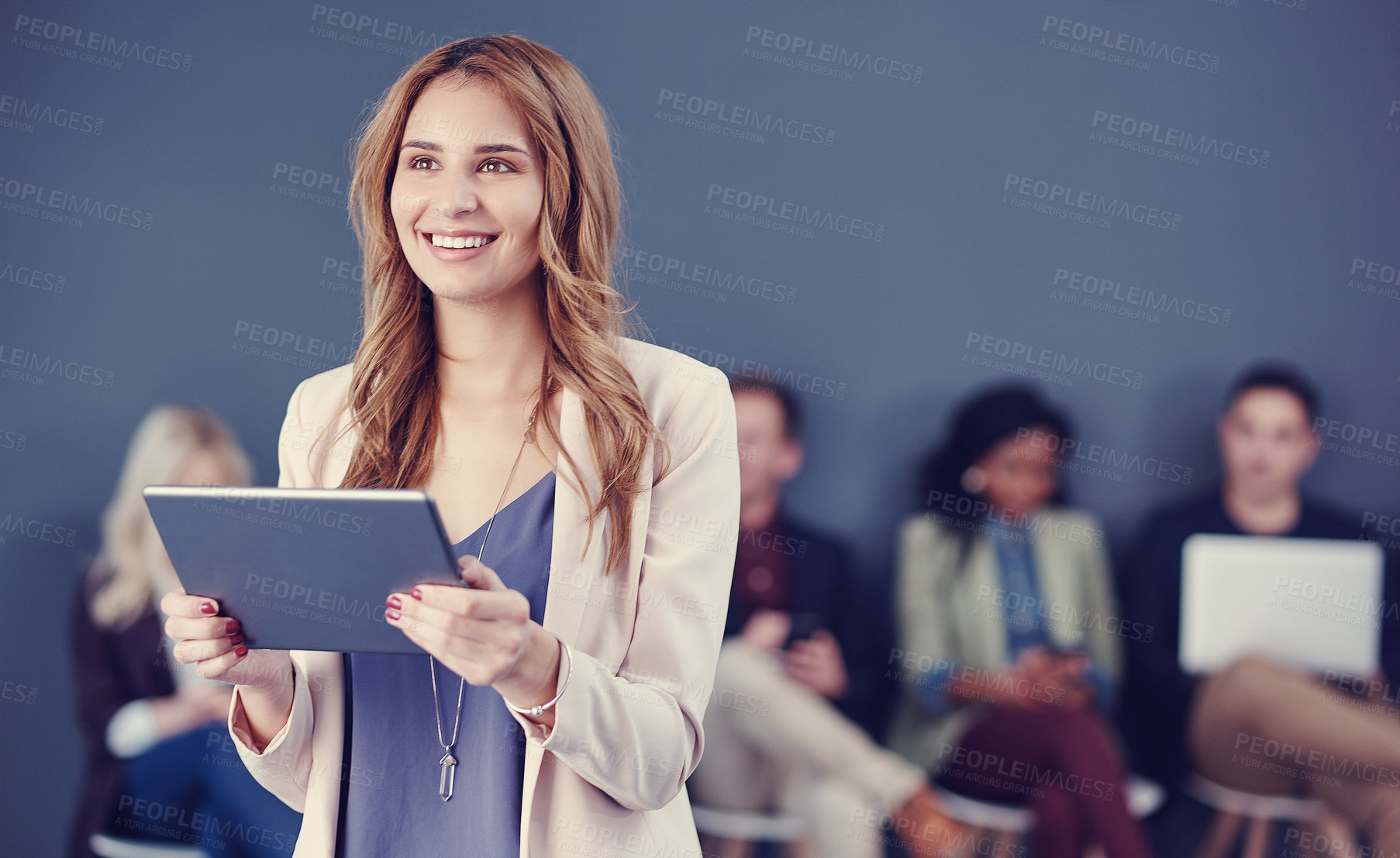 Buy stock photo Cropped shot of an attractive young businesswoman using a tablet with her colleagues in the background