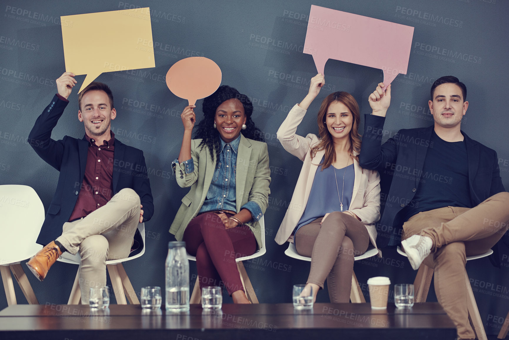 Buy stock photo Shot of a group of businesspeople holding up speech bubbles while waiting in line for an interview