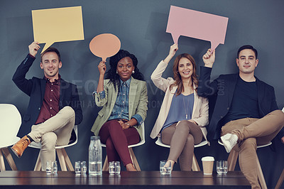 Buy stock photo Shot of a group of businesspeople holding up speech bubbles while waiting in line for an interview