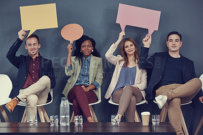 Buy stock photo Shot of a group of businesspeople holding up speech bubbles while waiting in line for an interview