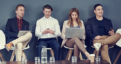 Buy stock photo Shot of a group of businesspeople using different wireless devices while waiting in line for an interview