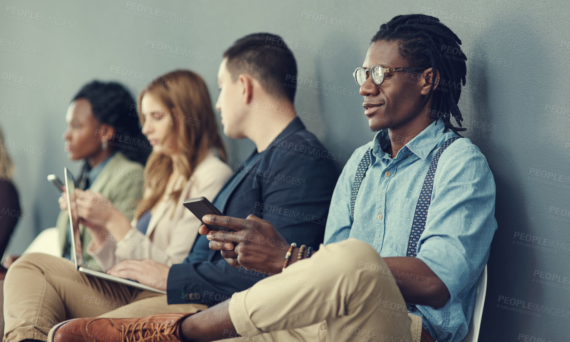 Buy stock photo Shot of a group of businesspeople using different wireless devices while waiting in line for an interview