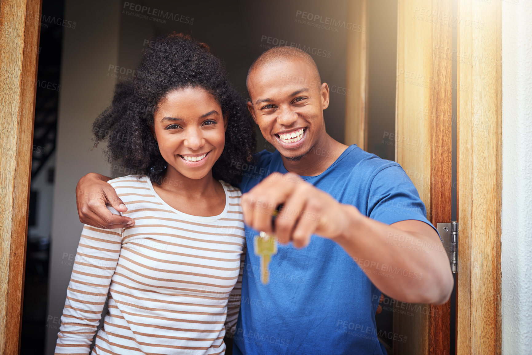Buy stock photo Portrait of a cheerful young couple standing together in a doorway while holding a pair of keys to their home