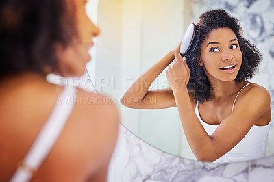 Buy stock photo Shot of an attractive young woman brushing her hair in the bathroom at home