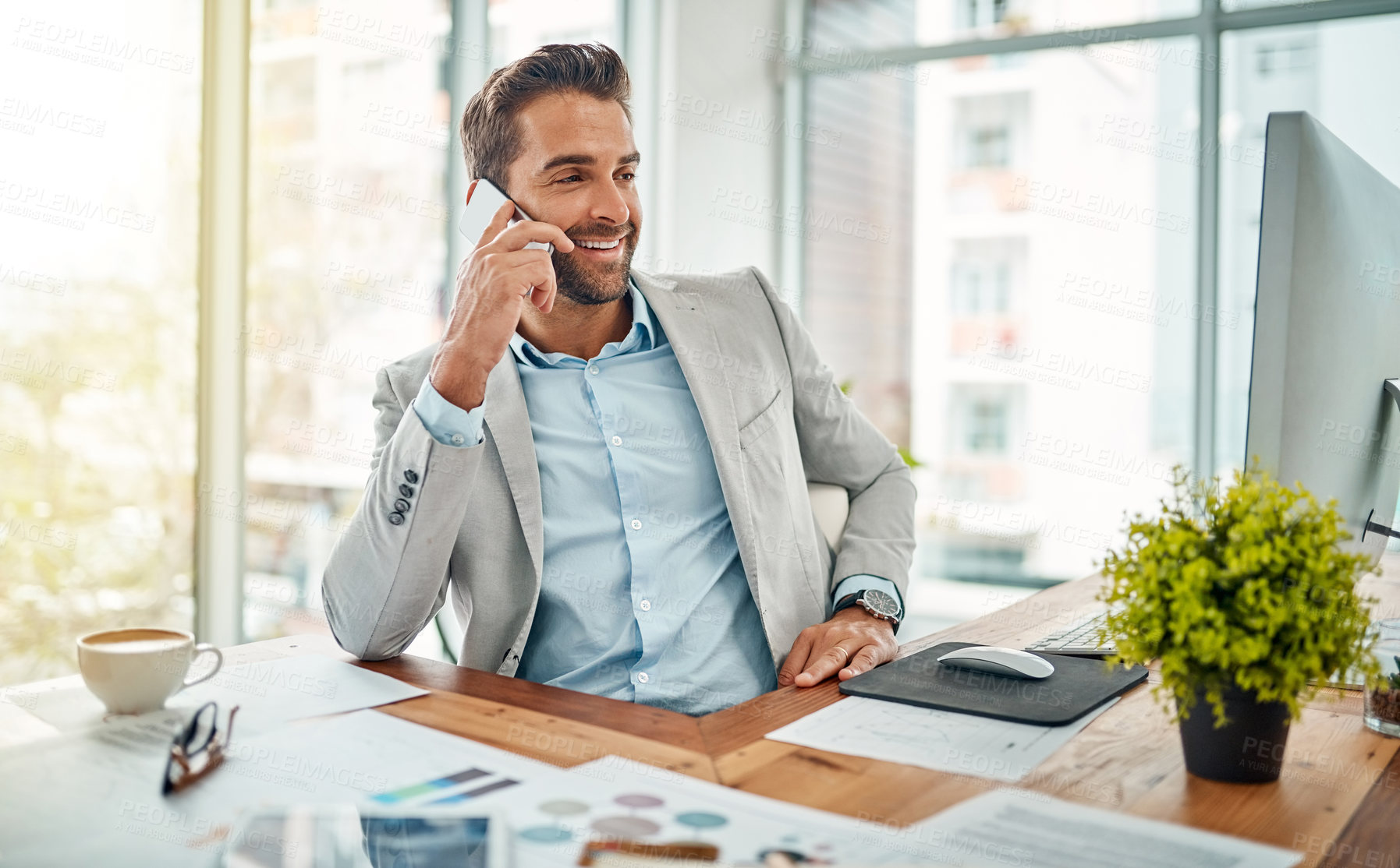 Buy stock photo Shot of a handsome young businessman talking on a cellphone in an office