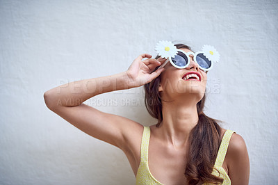 Buy stock photo Studio shot of a cheerful young woman wearing sunglasses while posing against a grey background
