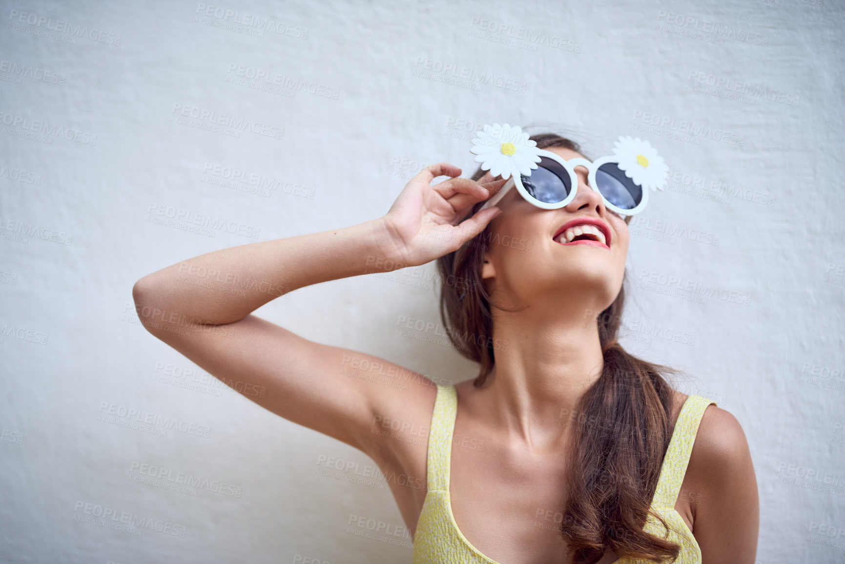 Buy stock photo Studio shot of a cheerful young woman wearing sunglasses while posing against a grey background