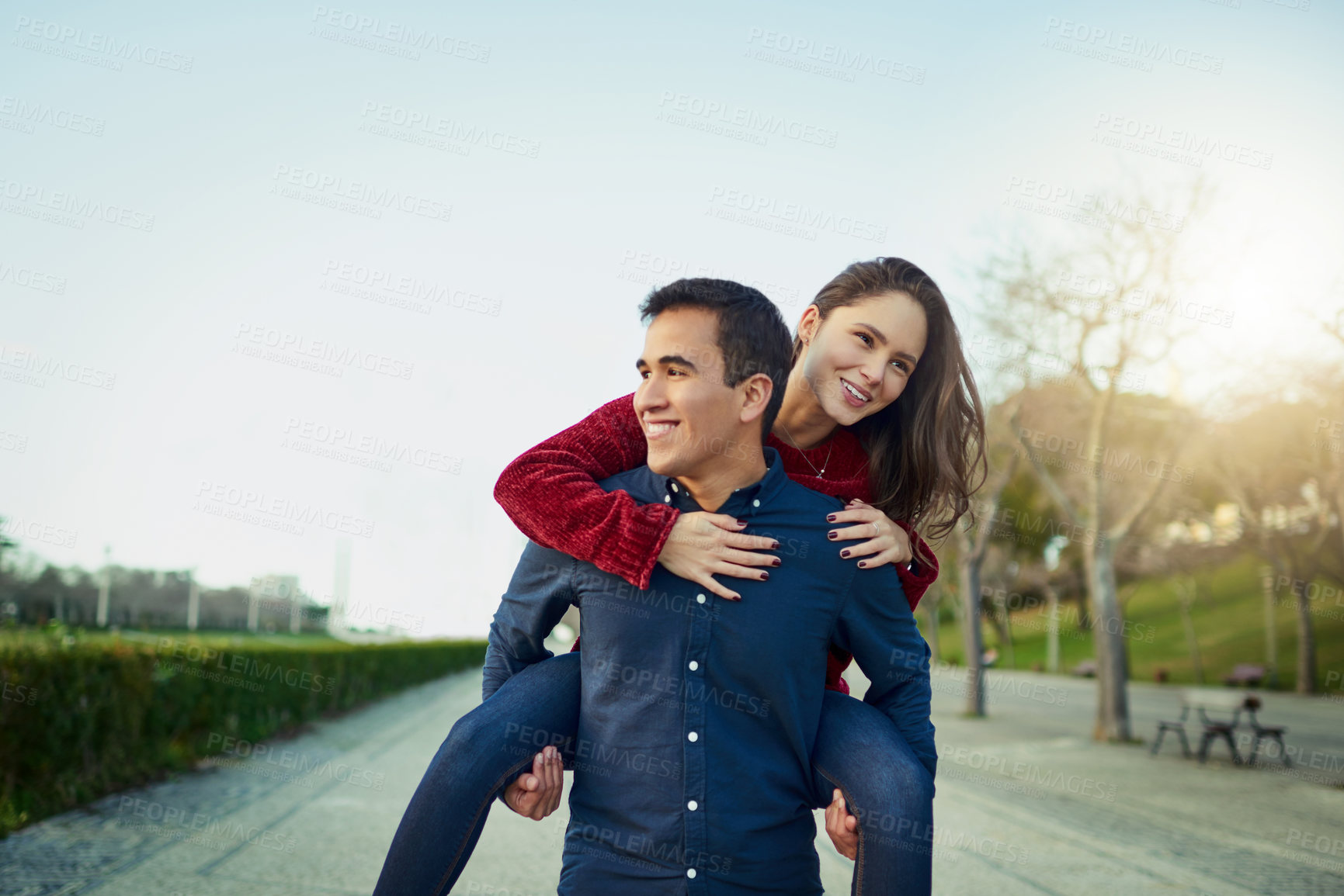 Buy stock photo Shot of a happy young couple enjoying a piggyback ride outdoors