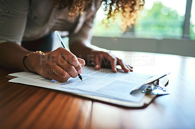 Buy stock photo Closeup shot of an unrecognizable woman filling in paperwork at a table