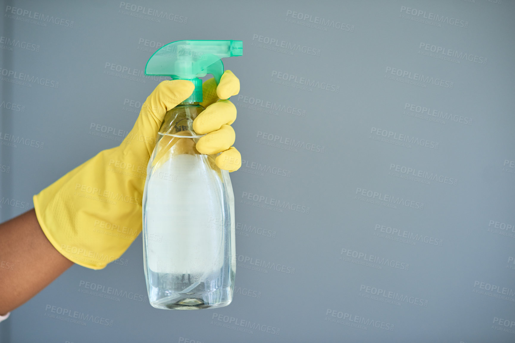 Buy stock photo Studio shot of an unrecognizable woman wearing rubber gloves and holding detergent against a gray background