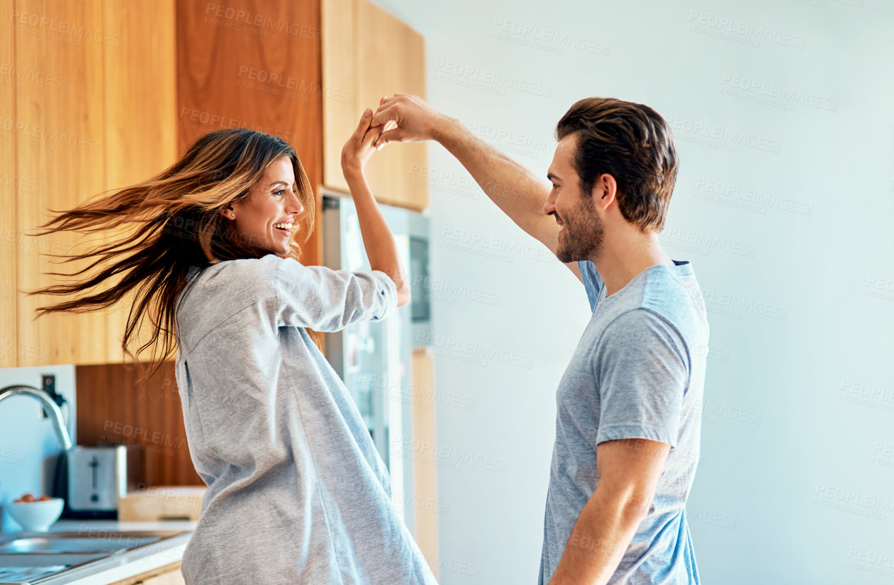 Buy stock photo Couple, spinning and dancing together in home, morning laughter and listening to music for bonding. People, holding hands and happy for support in movement, love and kitchen for marriage connection