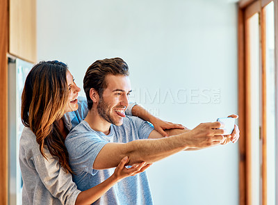 Buy stock photo Shot of a happy young couple taking a selfie together at home