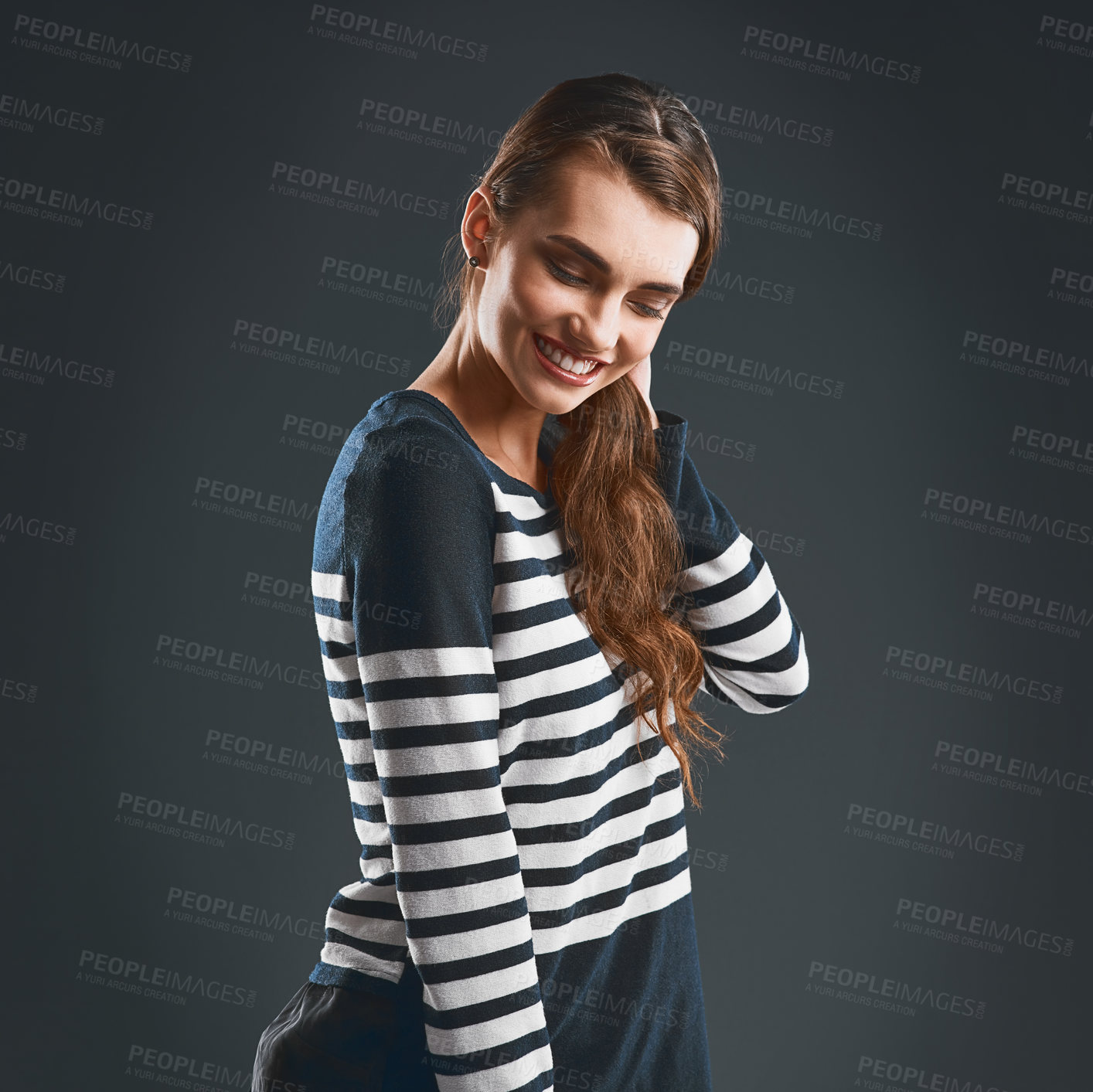 Buy stock photo Studio shot of a cheerful young woman holding her neck while standing against a dark background