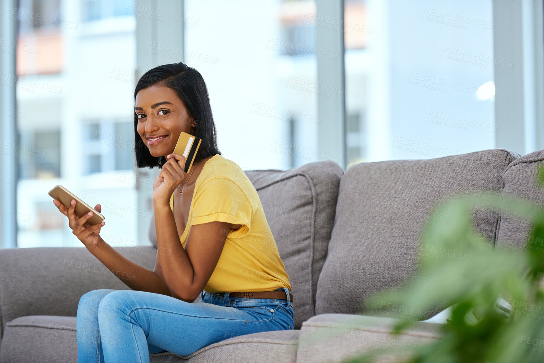 Buy stock photo Shot of a teenage girl using a cellphone and credit card at home