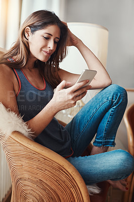 Buy stock photo Shot of an attractive young woman using her cellphone at home