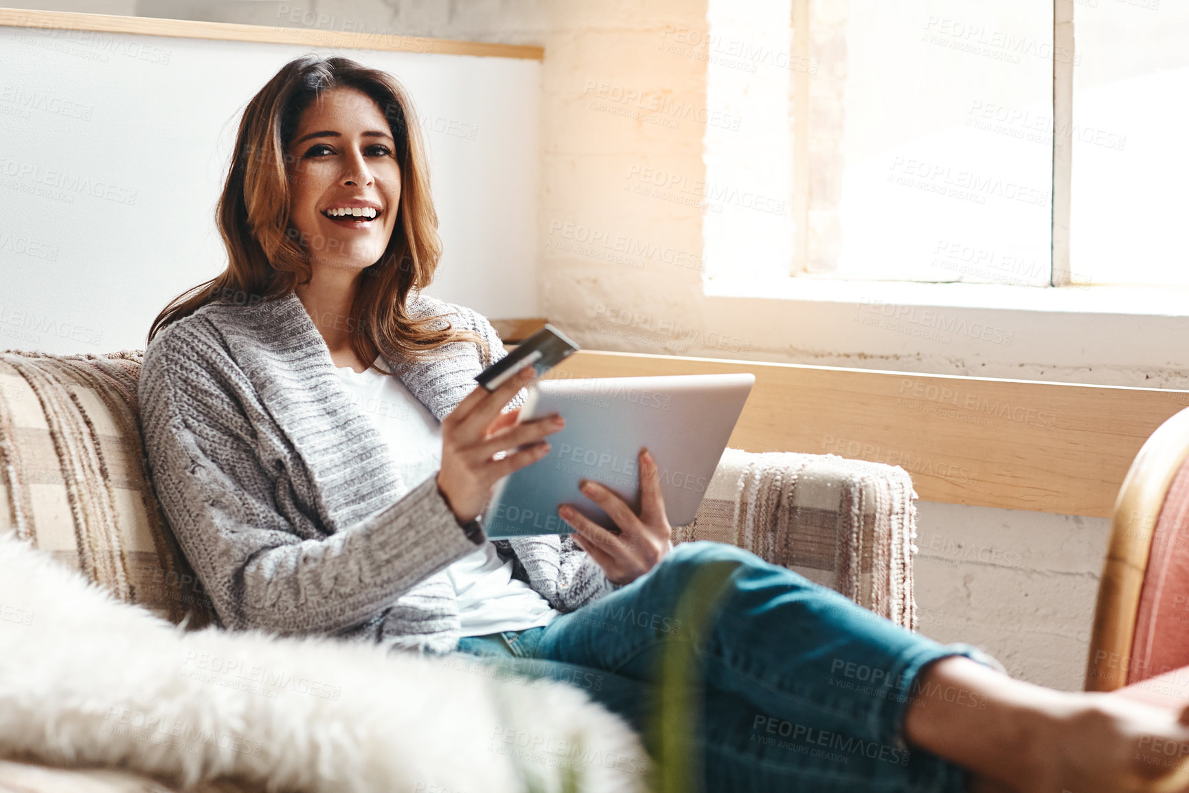 Buy stock photo Portrait of an attractive young woman using a digital tablet and credit card on the sofa at home