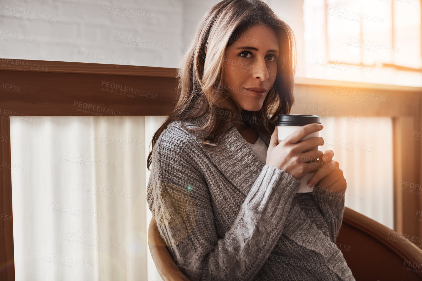 Buy stock photo Shot of an attractive young woman relaxing at home with a cup of coffee