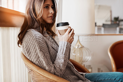 Buy stock photo Shot of an attractive young woman relaxing at home with a cup of coffee