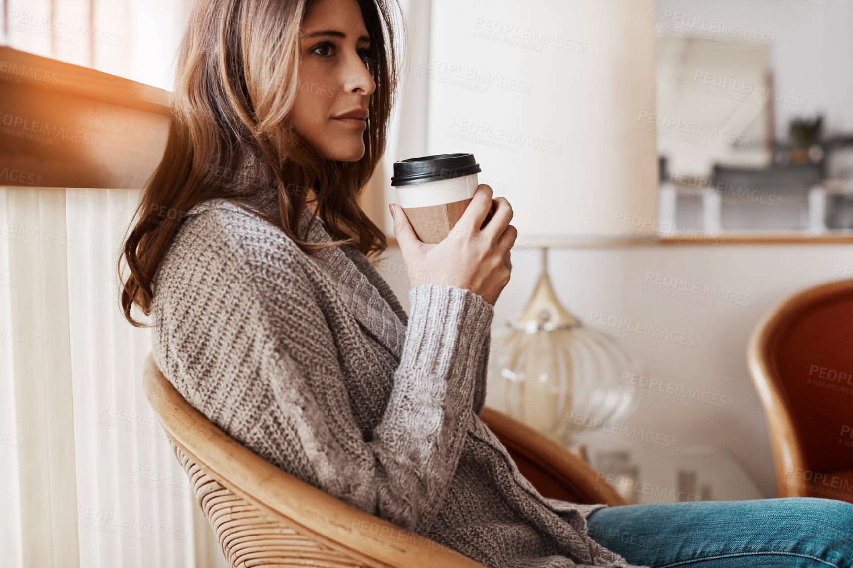 Buy stock photo Shot of an attractive young woman relaxing at home with a cup of coffee