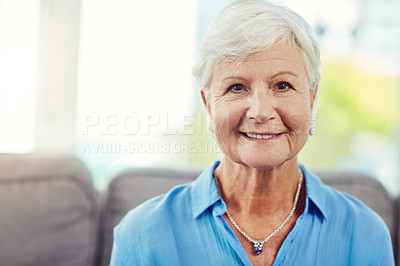 Buy stock photo Cropped portrait of a senior woman sitting on her sofa at home