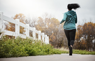 Buy stock photo Rearview shot of a young woman going for a run in nature