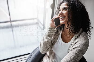 Buy stock photo Shot of a cheerful young woman relaxing while talking on her cellphone at home during the day