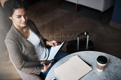 Buy stock photo Shot of a young businesswoman reading through a business folder while waiting for her flight in an airport lounge