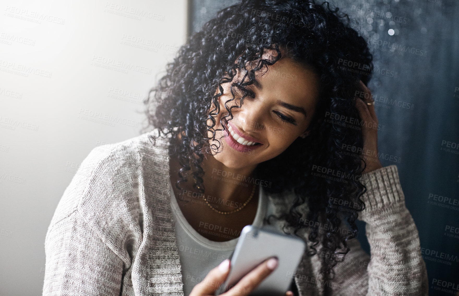 Buy stock photo Shot of a cheerful young woman relaxing while texting on her cellphone at home during the day