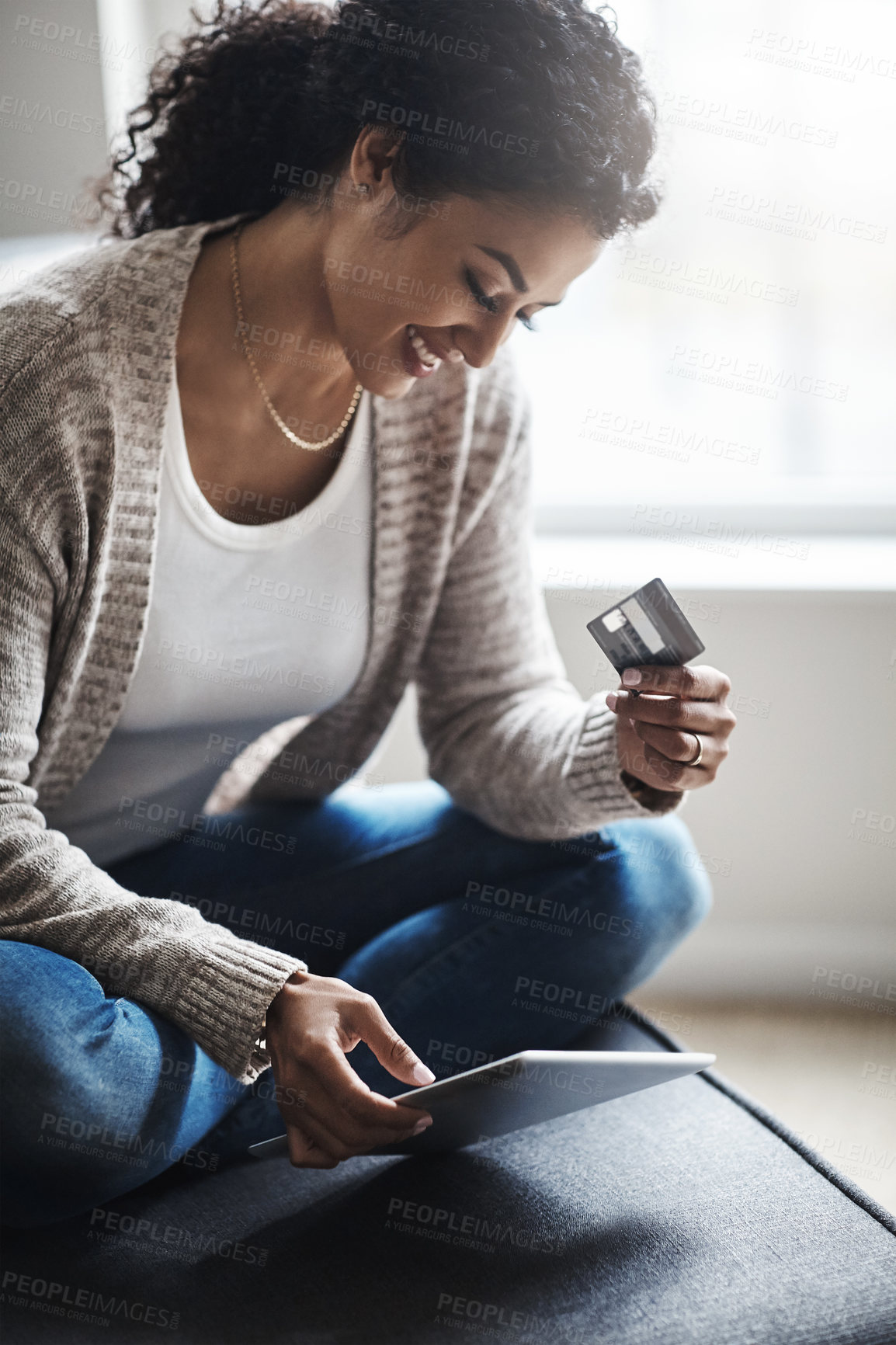 Buy stock photo Shot of an attractive young woman using a digital tablet and credit card at home