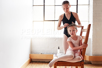Buy stock photo Shot of an adorable little girl getting her hair tied up by an older girl in a ballet studio