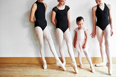 Buy stock photo Shot of a group of young ballerinas teaching a little girl ballet in a dance studio