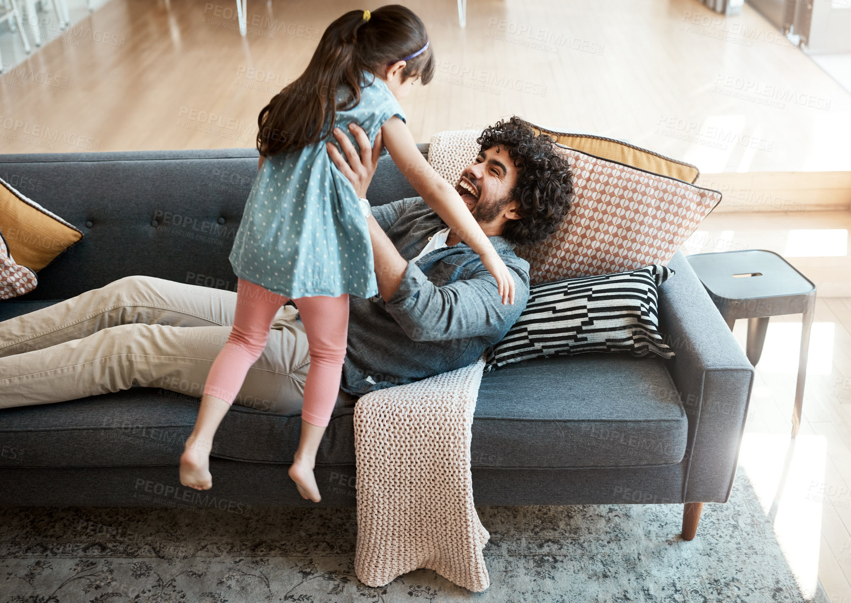 Buy stock photo Excited, dad and lifting of girl on sofa for support, gratitude and bonding together in living room. Playful, family and man with love of daughter at home for appreciation, trust or care in childhood