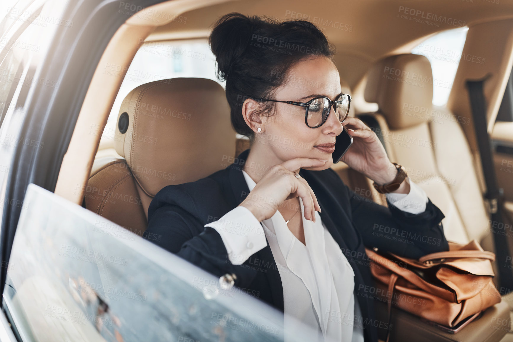 Buy stock photo Shot of a confident young business woman seated in a car as a passenger and talking on her cellphone while  going to work