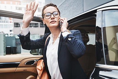 Buy stock photo Shot of a confident young businesswoman getting out of a car while holding a cellphone and raising her hand outside during the day