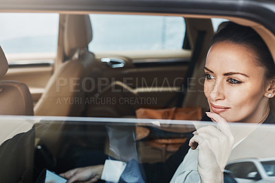 Buy stock photo Shot of a confident young businesswoman seated in a car as a passenger while busy on her phone and looking out of the window