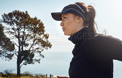 Buy stock photo Shot of a determined young woman going for a jog on her own with a view of the city in the background