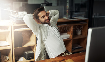 Buy stock photo Shot of a handsome young businessman taking a break while working late in an office