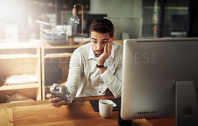 Buy stock photo Shot of a handsome young businessman holding an alarm clock and looking stressed out while working late in an office
