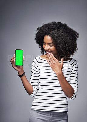 Buy stock photo Studio shot of a young woman showing a smartphone with a green screen against a gray background