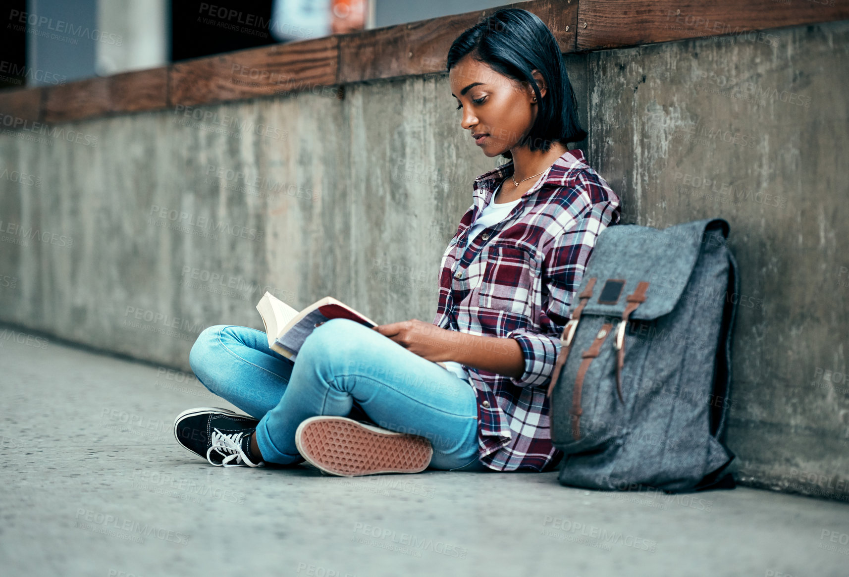 Buy stock photo Shot of a young female student reading a book outside on campus