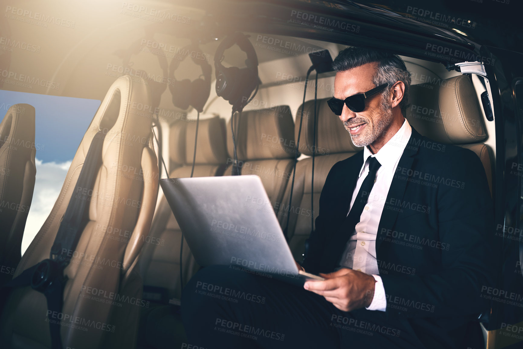 Buy stock photo Businessman, travel and flying with laptop of FBI, spy or secret service for surveillance in helicopter. Happy man or special agent on computer or technology in air or flight for safety or coverage