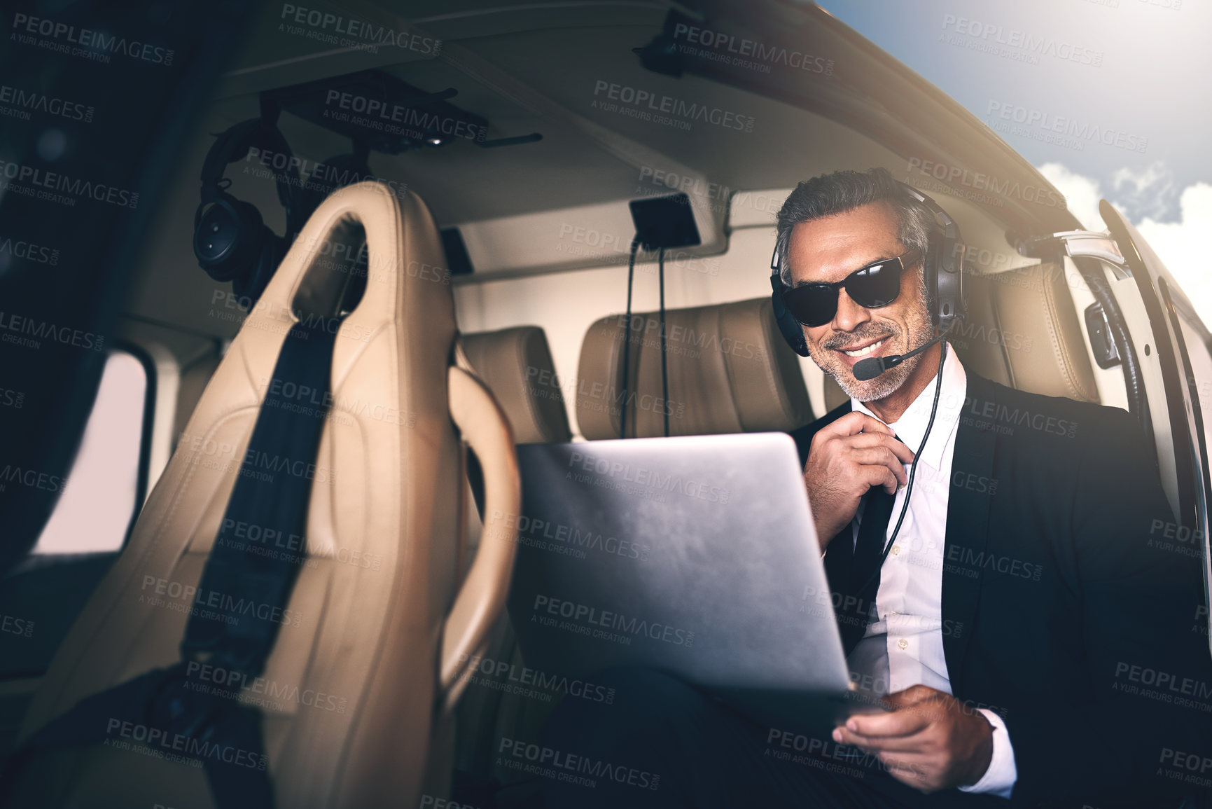 Buy stock photo Shot of a mature businessman using a laptop while traveling in a helicopter
