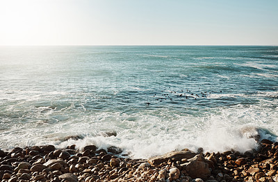 Buy stock photo Shot of water crashing against some boulders at the beach