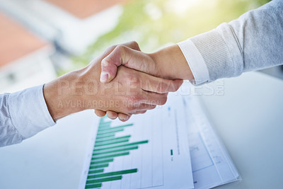 Buy stock photo Closeup shot of two businesspeople shaking hands over some paperwork in an office