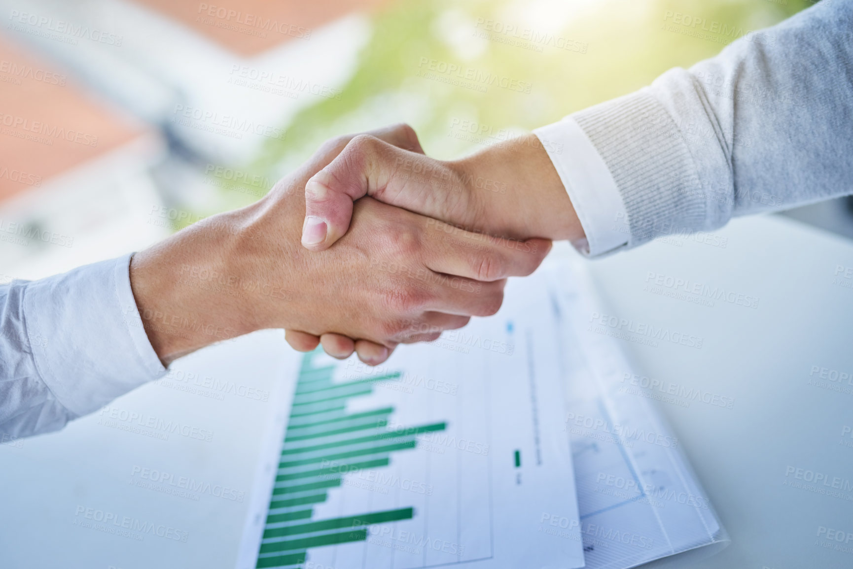 Buy stock photo Closeup shot of two businesspeople shaking hands over some paperwork in an office
